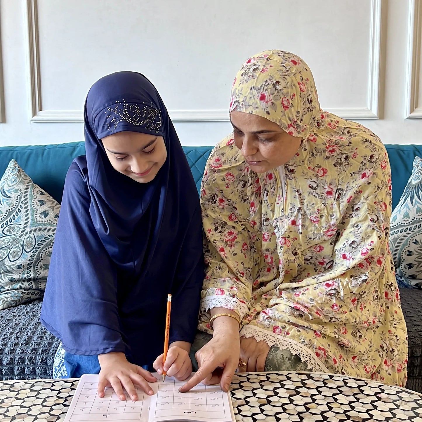 Two women sitting at a table with books and papers, engaged in a discussion.