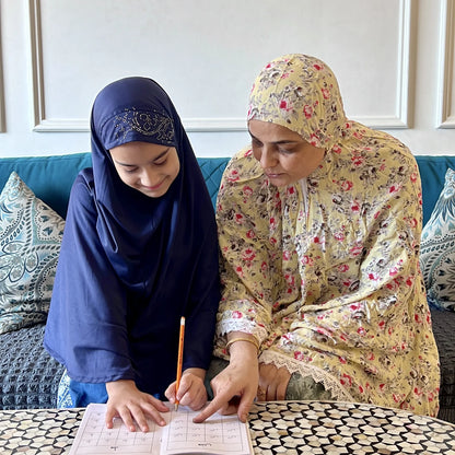 Two women sitting at a table with books and papers, engaged in a discussion.