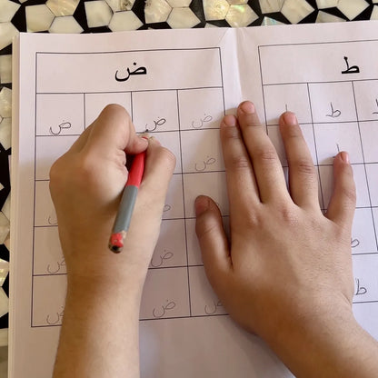 Person writing on a worksheet with a pen, on a patterned surface.